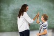 © WavebreakMediaMicro - Happy teacher and school boy giving high five in classroom
