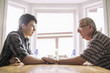 © Maskot - Side view of grandfather consoling grandson at table