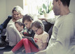 © Maskot - Family of five sitting on sofa at home