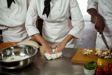 Wall Mural - Mid section of head chef making pizza dough