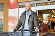 © Maskot - Mid adult man with shopping cart standing outside supermarket