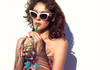 Summer style portrait of young attractive woman wearing sunglasses drinking water. Tropical summer holiday fashion beauty concept