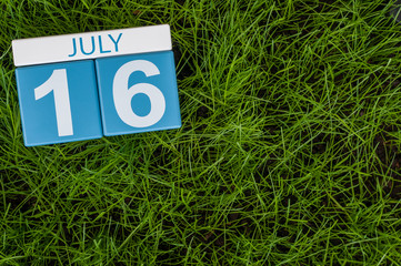 July 16th. Image of july 16 wooden color calendar on greengrass lawn background. Summer day, empty space for text