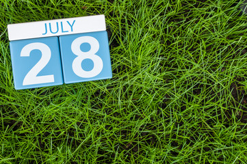 July 28th. Image of july 28 wooden color calendar on greengrass lawn background. Summer day, empty space for text