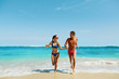 © puhhha - Couple Fun On Beach. Romantic People In Love Running On Sand At Luxury Sea Resort. Handsome Happy Man, Beautiful Smiling Woman Laughing Together On Summer Travel Vacation. Relationships, Summertime