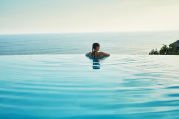 luxury resort. woman relaxing in infinity swimming pool water. beautiful happy healthy female model 