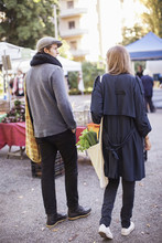 Rear View Of Young Couple With Leafy Vegetables At Market