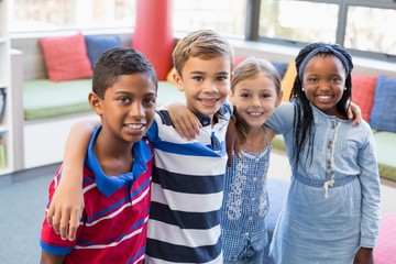 Canvas Print - Smiling school kids standing with arm around in library