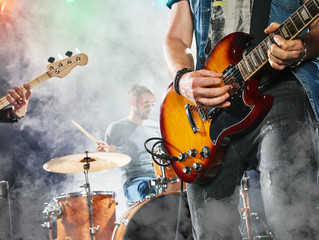 rock band performs on stage. guitarist, bass guitar and drums. guitarist in the foreground. close-up
