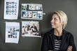 © Maskot - Mid adult businesswoman smiling while looking at photographs on wall in office