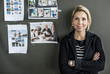 © Maskot - Portrait of mid adult businesswoman standing arms crossed against wall in office