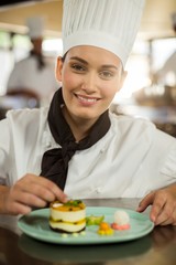 Wall Mural - Portrait of female chef finishing dessert plates