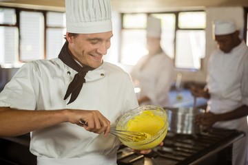 Wall Mural - Smiling chef mixing dough