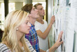 © Maskot - Three students standing by notice board