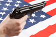 Gun in hand with ruffled national flag on background - United States
