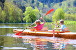Back view of two boys kayaking on the river. Active happy friends, teenage schoolboys, having fun together enjoying adventurous experience with kayak on a sunny day during summer vacation
