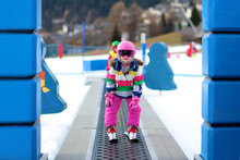 Happy Child Enjoying Winter Vacation In Alpine Resort In Austria. Active Sportive Toddler Girl Learning To Ski. Kid Having Fun In Ski School Going Up To The Slope On The Magic Carpet Lift.