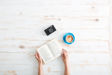 Female hands holding book on the wooden desk