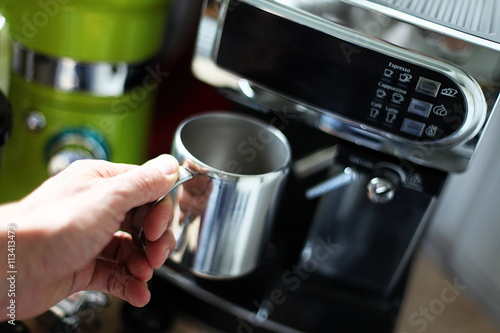 Fotografie, Obraz Hand führt eine Tasse zur Kaffeemaschine