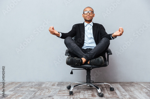 Fotografía Relaxed african young man sitting and meditating on office chair
