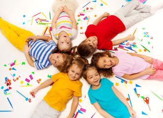Funny kids laying among school office supplies