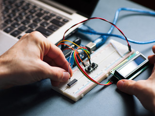 Microchip manual connecting to microcontroller. Top view on engeneer hands working with microcontroller. Closeup of microcontroller