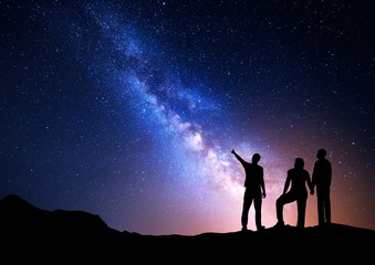 Wall Mural - colorful milky way with silhouette of a standing man pointing finger in night starry sky and his par