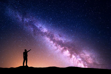 Wall Mural - milky way with silhouette of a standing man pointing finger in night starry sky on the hill. colorfu