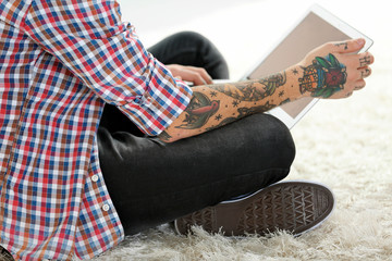 Poster - Young man with tattoo using laptop on a floor at home