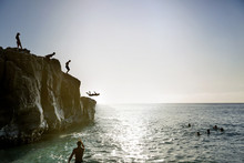 Friends Jumping From Cliff Into Ocean
