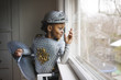 © Cavan Images - Little boy dressed up in armor costume looking out through window at home