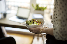 Midsection Of Woman Holding Salad Bowl At Home Office