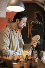 Man Making Wooden Figurine In Workshop