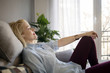 © Cavan Images - Side view of relaxed woman listening music while sitting on sofa at home