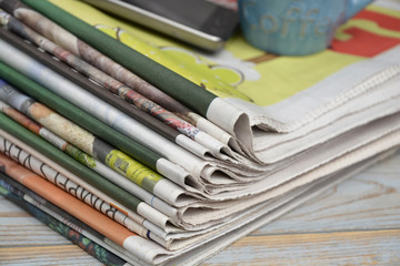 Close-up of a stack of colored papers, mpbile phon and coffe cup on a wooden table background
