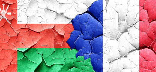 Oman flag with France flag on a grunge cracked wall