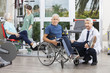 © Tyler Olson - Doctor Holding Senior Man's Leg In Wheelchair At Fitness Center