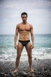 © theartofphoto - Young shirtless athletic man standing in water by ocean shore
