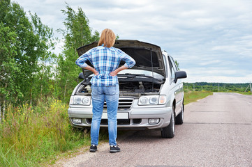 Wall Mural - Woman looking under hood of broken car