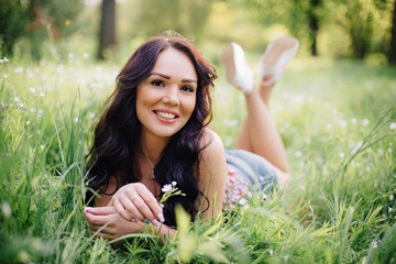 sunny summer day, a beautiful young woman lying on the grass