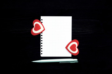 A blank sheet of paper, pen and two hearts on a wooden background. Photo in vintage style