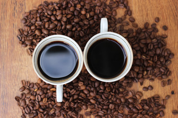 Two White Coffee mug with coffee beans on a wooden background closeup