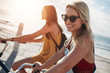 © Jacob Lund - Smiling young woman riding bicycle with her friend