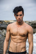 © theartofphoto - Young shirtless athletic man standing in water by ocean shore