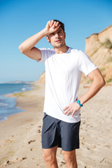 Sticker - Tired young sportsman standing and relaxing on the beach