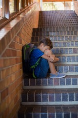 Wall Mural - Sad schoolboy sitting alone on staircase