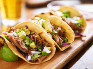 Wall Mural - three  pork carnitas street tacos in yellow corn tortilla with avocado, onion, cilantro and cabbage