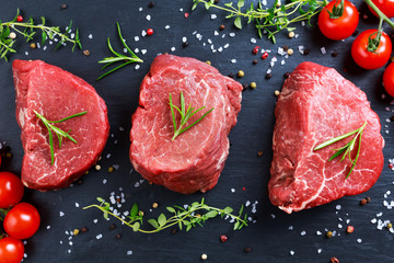 Fresh Raw Beef steak Mignon, with salt, peppercorns, thyme, tomatoes.