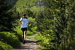 running man in white sportswear and shorts training on the mountain trail