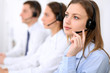 © rogerphoto - Young beautiful business woman in headset. Call center. Male call operator in headset at the background.